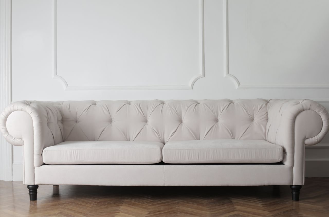 Luxurious white sofa in a modern minimalist interior with wooden flooring.